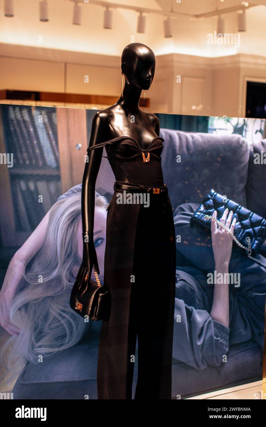 Stylish mannequin in a boutique window dressed in a black pants with belt and holding small leather handbag Stock Photo