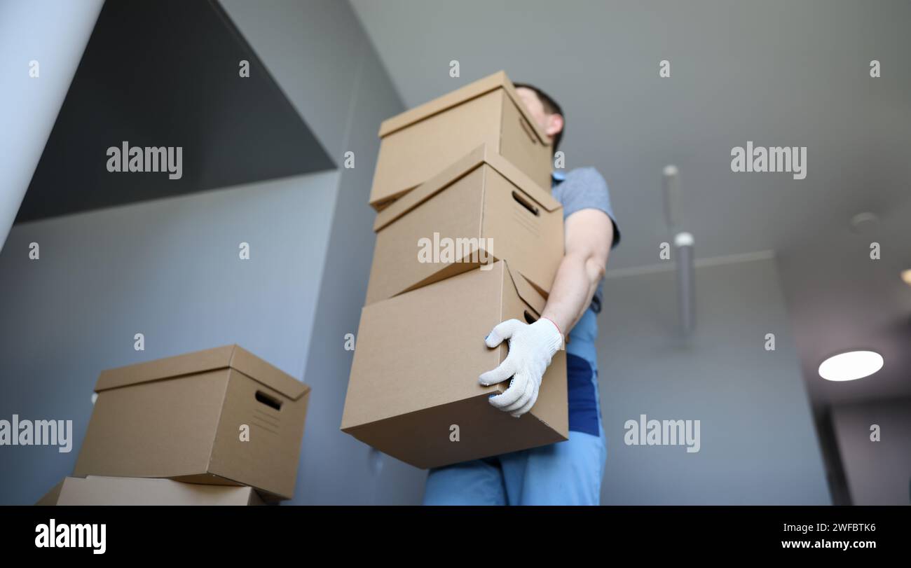 Man work clothes and gloves carries cardboard boxes Stock Photo - Alamy