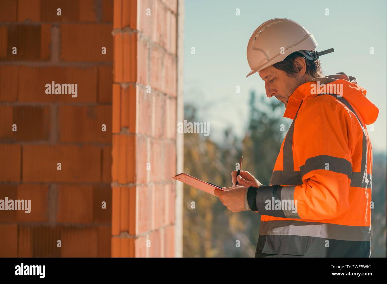 Construction engineer making notes and remarks during building site inspection, selective focus Stock Photo