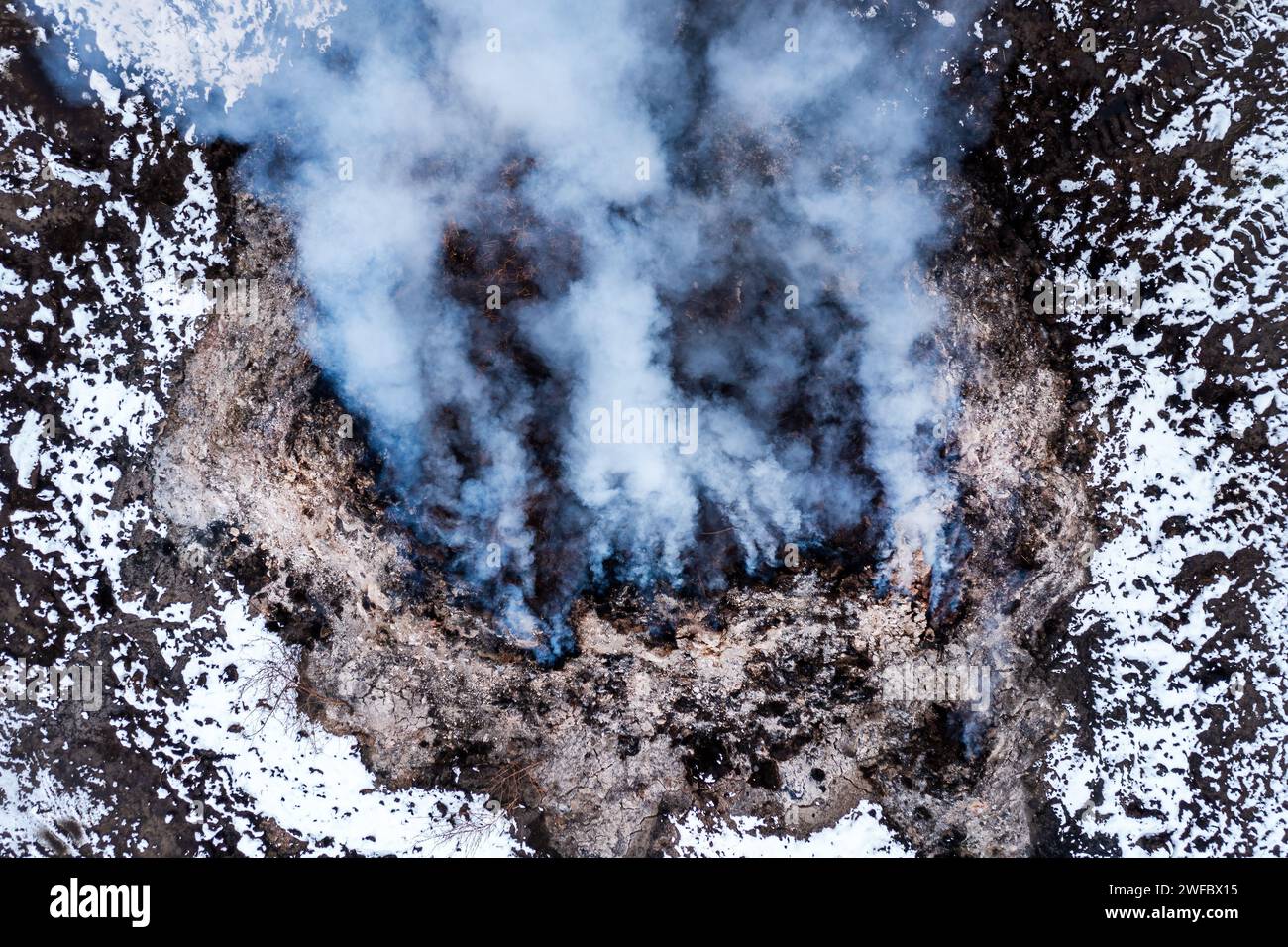 Burning manure pile at farm, air pollution and contamination, aerial shot from drone pov, high angle view Stock Photo