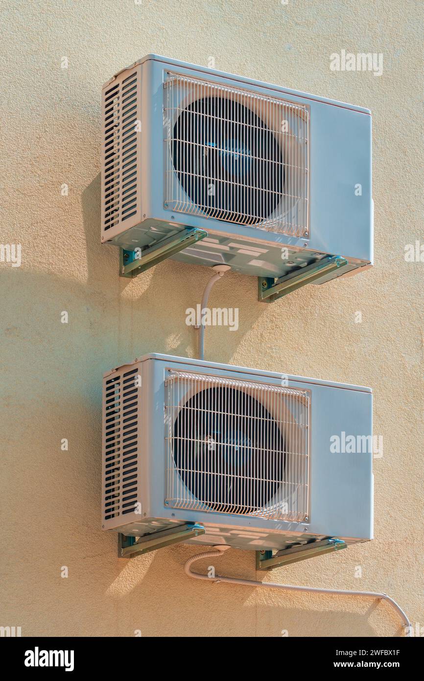 Two air conditioning external units mounted on th wall of residential building in summer Stock Photo