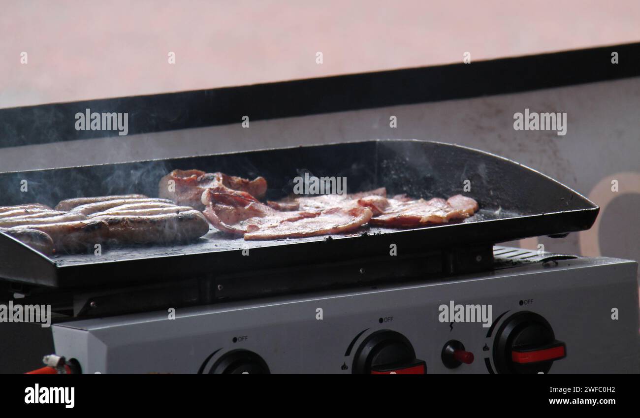 Cooking Bacon and Sausages on a Portable Gas Stove Stock Photo Alamy