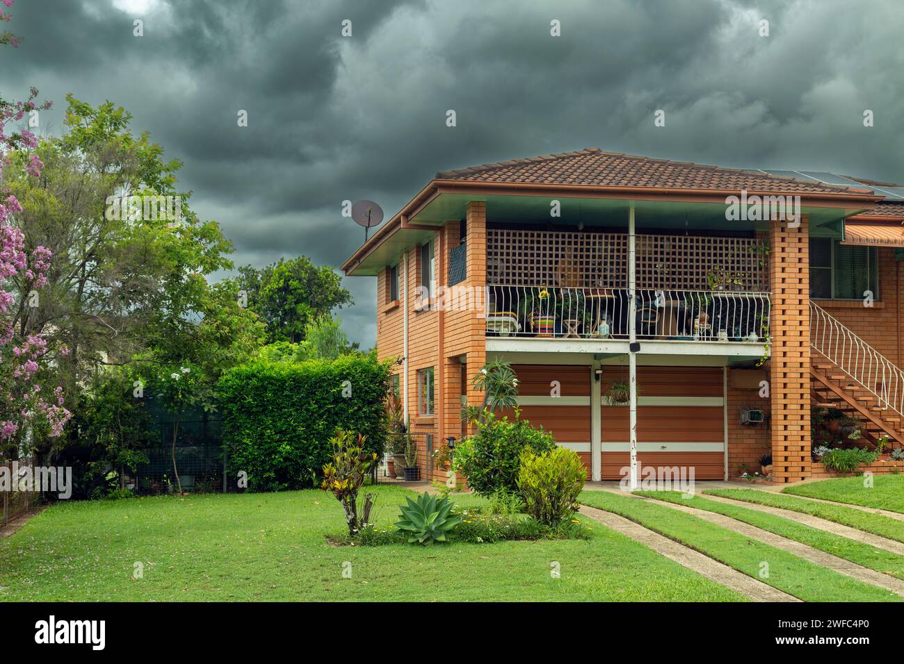 Storm clouds and a two-story brick house. Stock Photo