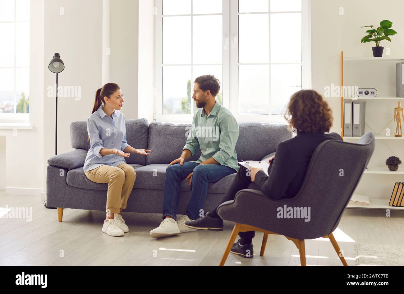 Young couple talking about marriage problems sitting at family psychologist office. Stock Photo