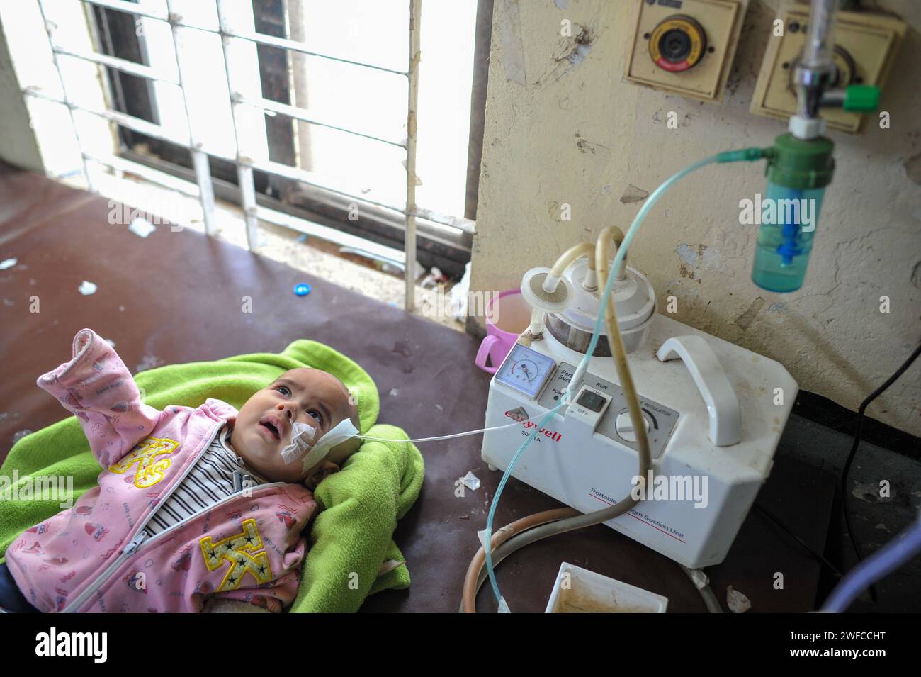 A senior nurse is providing medical care to a child in Sylhet MAG Osmani Medical College Hospital. Even though the severity of winter has decreased, the number of children suffering from cold has not decreased in Osmani Hospital. Infants between the ages of 6 months and one and a half years are rushing to the hospital with pneumonia and bronchopneumonia complications. The doctors in charge of the children's ward said that although an average of 50 children were admitted daily in December, around 30 are currently being admitted. Sylhet, Bangladesh. Stock Photo