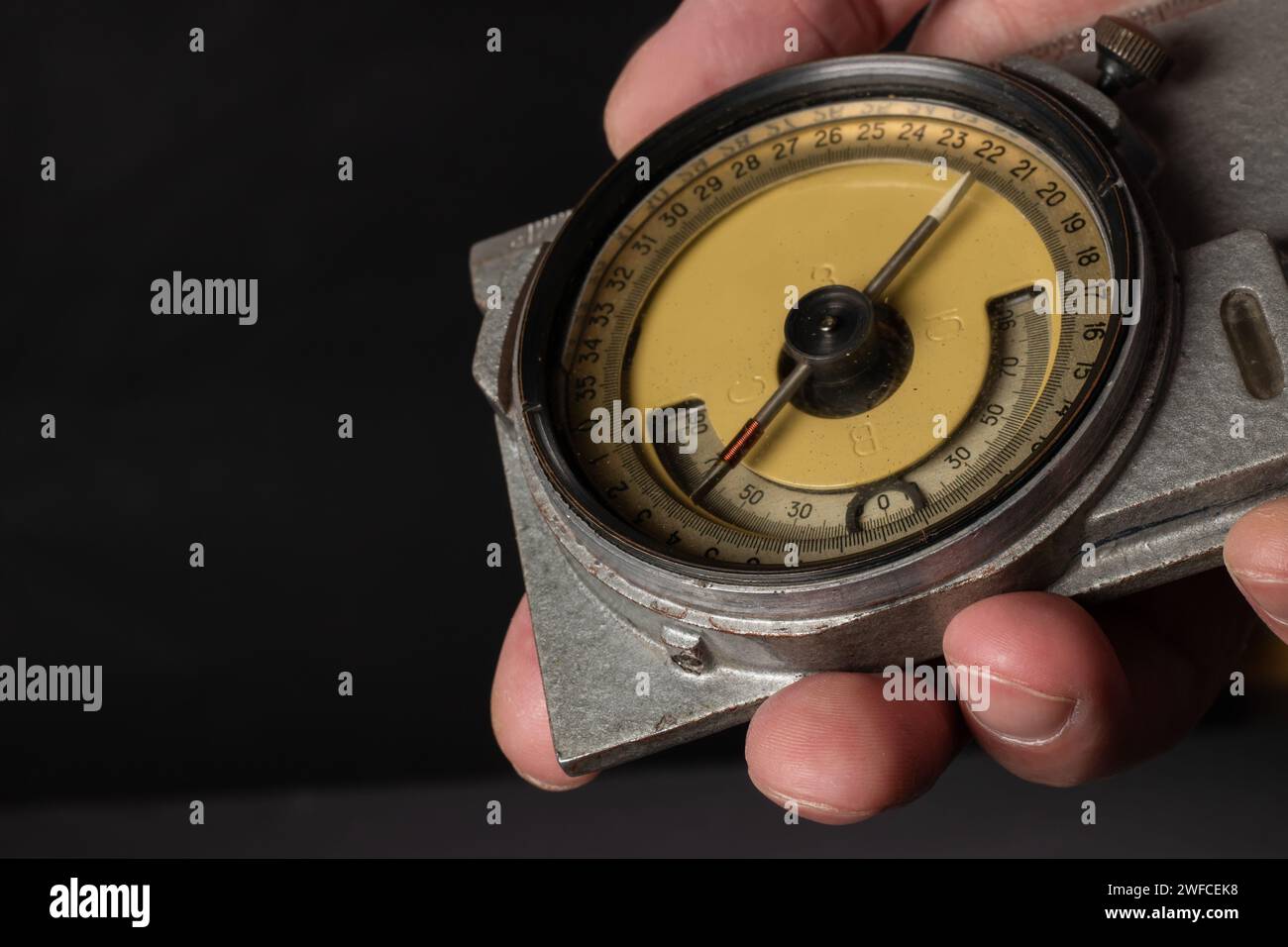 Old mining compass in hand on dark background close up. Stock Photo