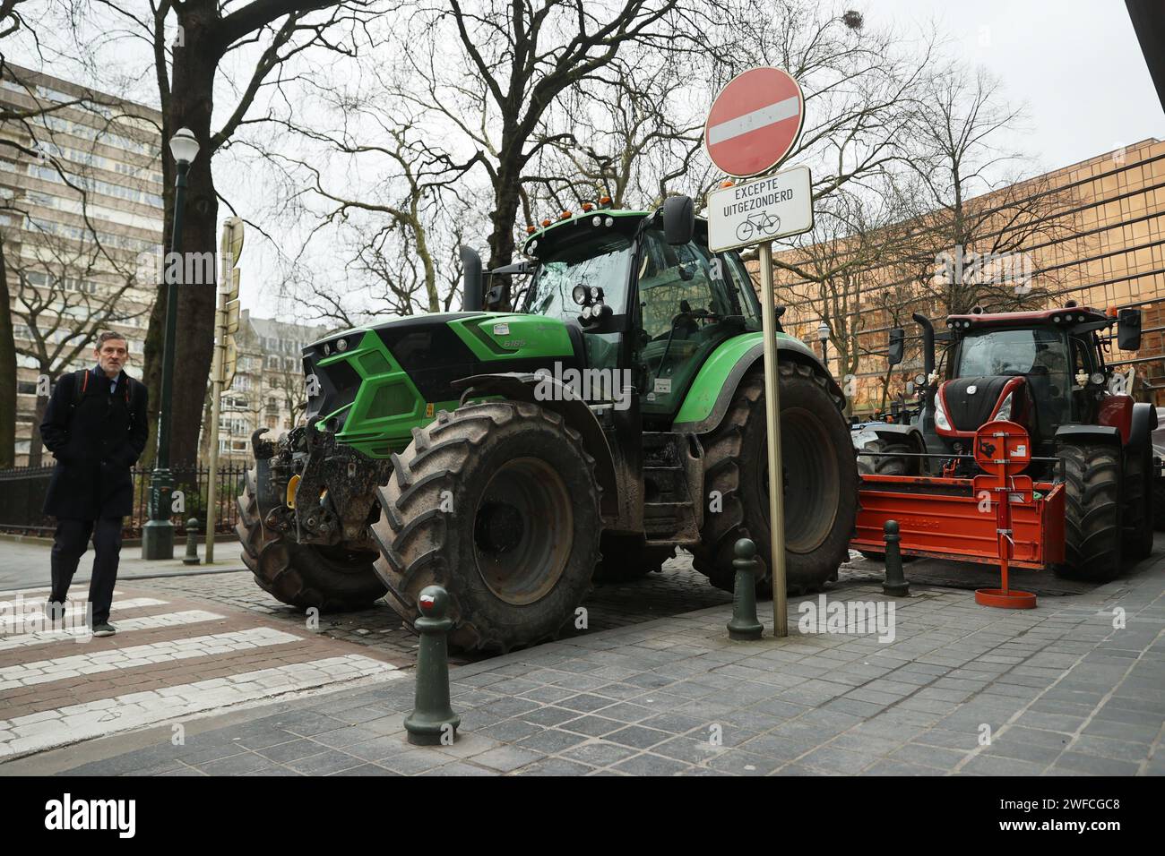 Brussels, Belgium. 30th Jan, 2024. A pedestrian walks past a tractor