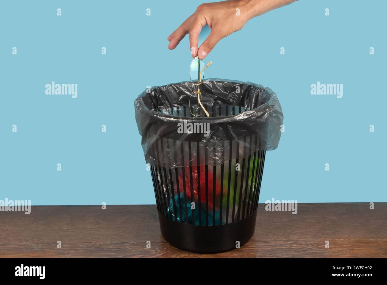 throw glasses in trash bin, glasses in hand in front of trash can