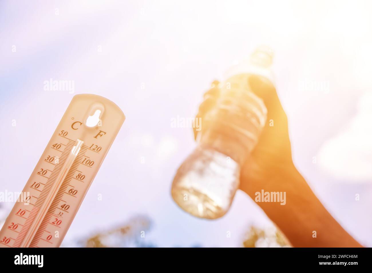 hot temperature,Thermometer and water bottle on sky with sun shining in