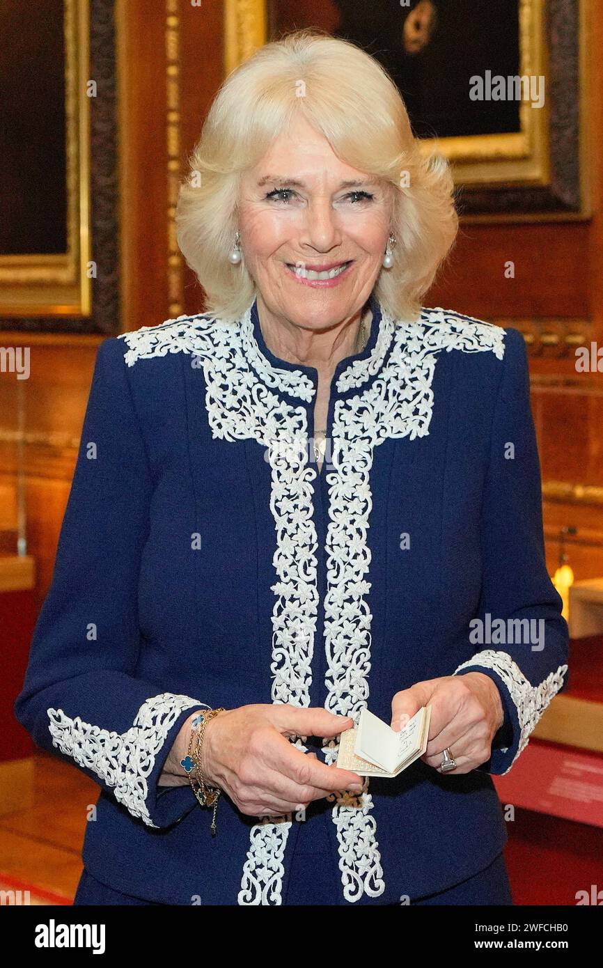 Queen Camilla holds a miniature book during a reception at Windsor ...