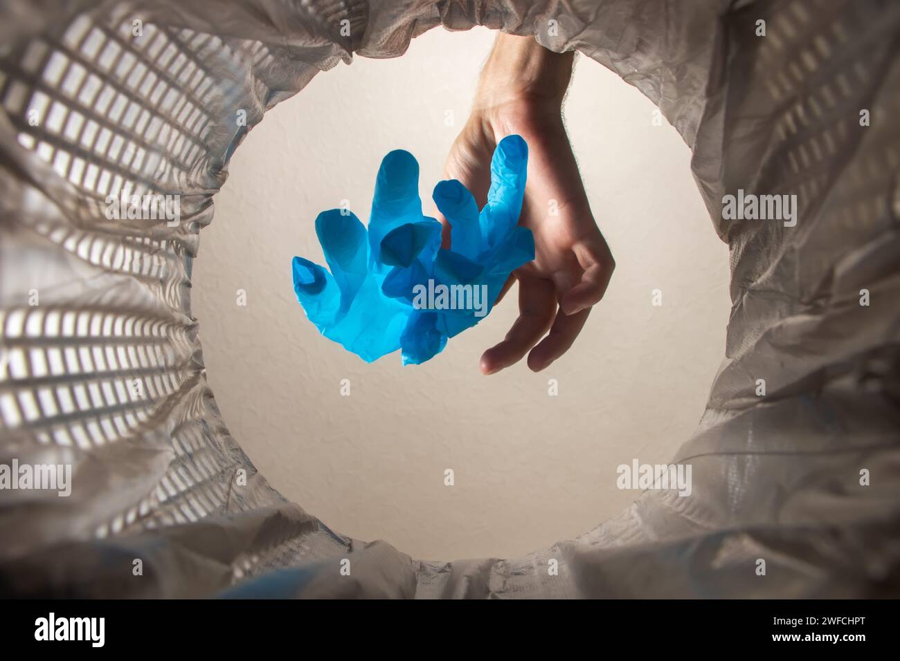 healthcare professional throwing away blue disposable latex gloves in