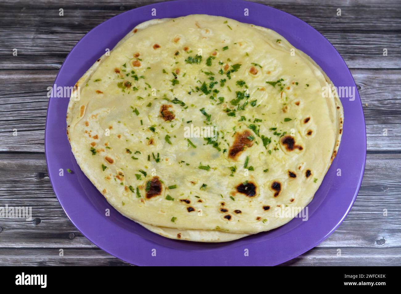 Indian naan bread baked inside a very hot clay tandoor oven, delicious, soft, puffy, airy, with the beautiful golden brown spots on the surface, India Stock Photo