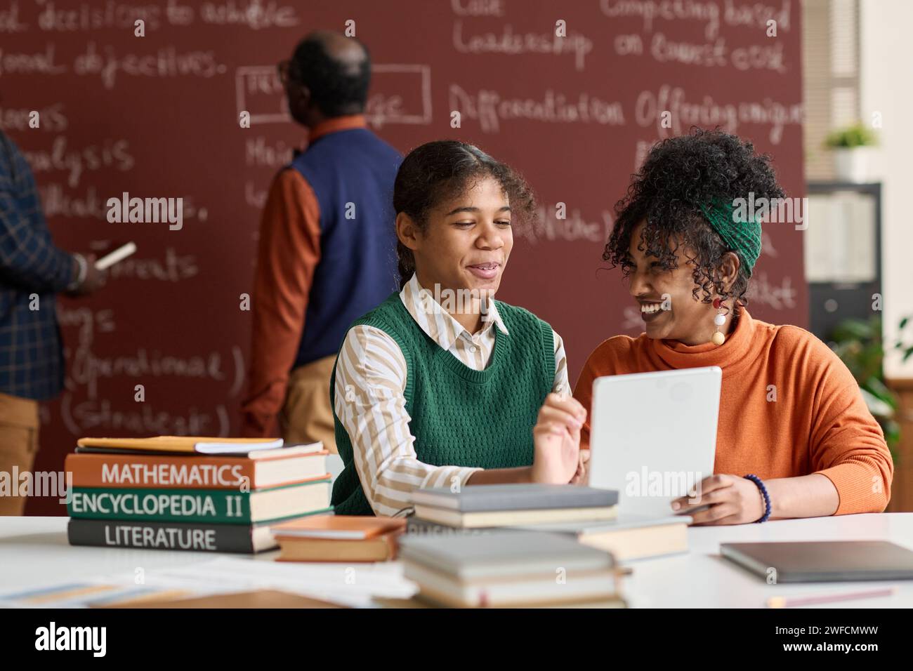 Portrait of two cheerful Black girls laughing while enjoying schoolwork in college classroom copy space Stock Photo