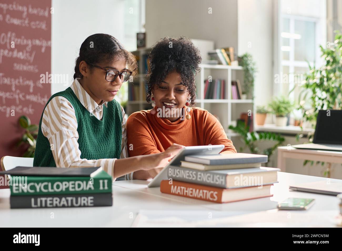 Portrait of two young Black girls using digital tablet in school classroom and working on online presentation copy space Stock Photo