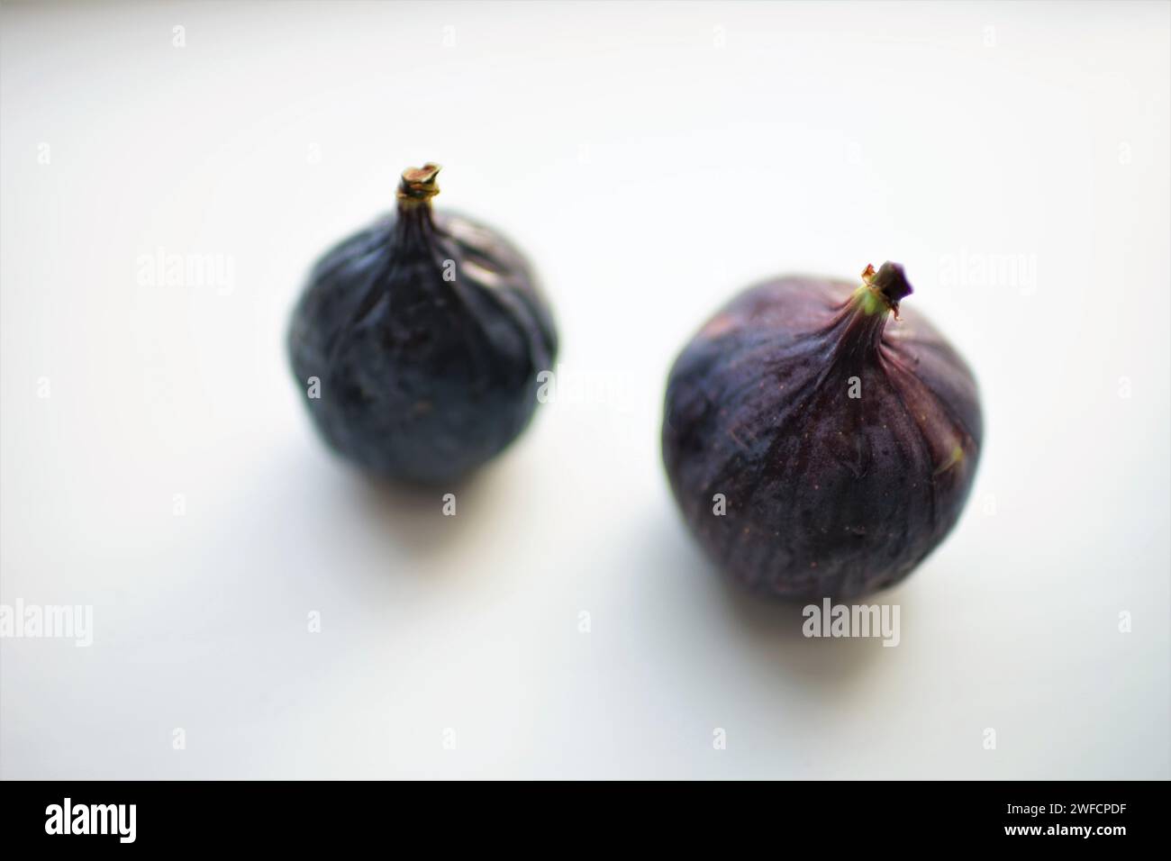 Two ripe sweet figs on white table. Selective soft focus. Blurred. Stock Photo