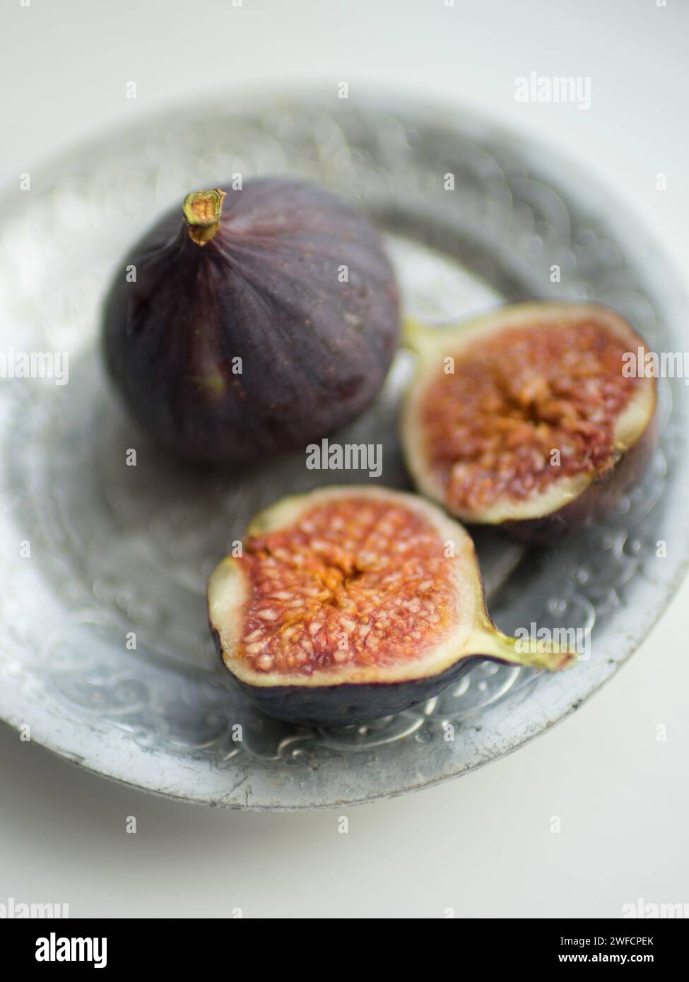 One whole fig and the second cut in half on a white table. Selective focus Stock Photo