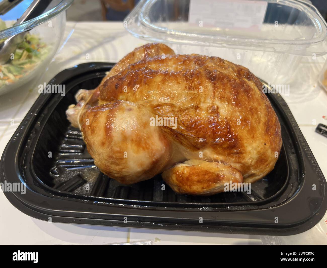 Costco roasted whole chicken in a takeout container on a dining table