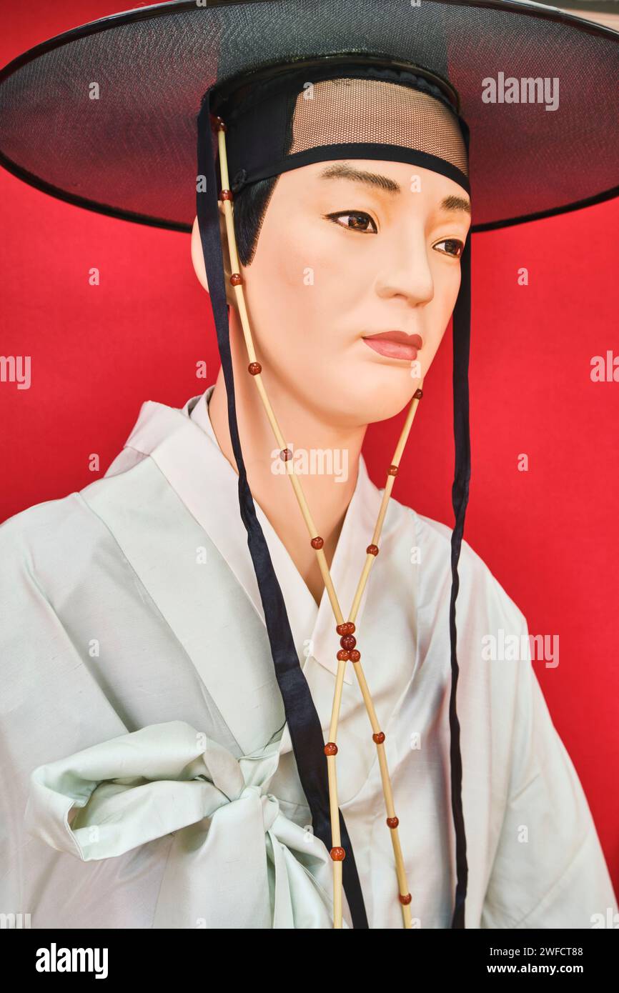 A display of old, traditional, ceremonial clothing worn by someone of Korean descent. A man in off white silk robe and black, silver hat. At the Centr Stock Photo