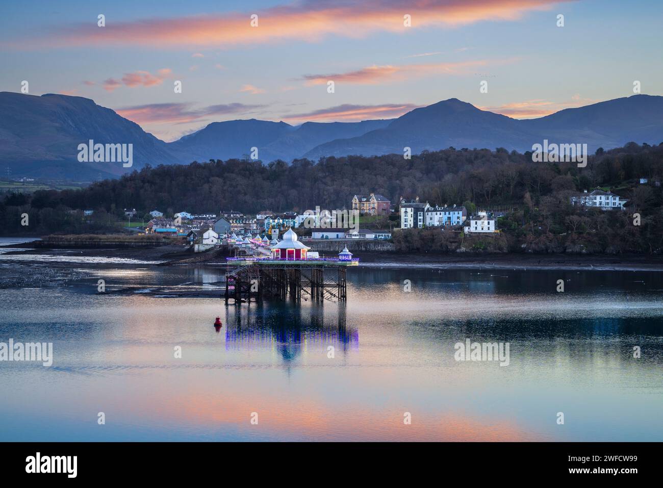 Bangor Garth Pier extending into the Menai Strait at sunset, with distant mountains of Snowdonia.