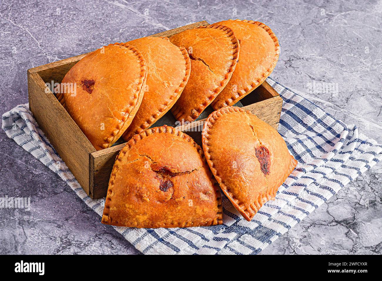 Three pastries in a rustic wooden box placed on a charming blue and white checked cloths Stock Photo