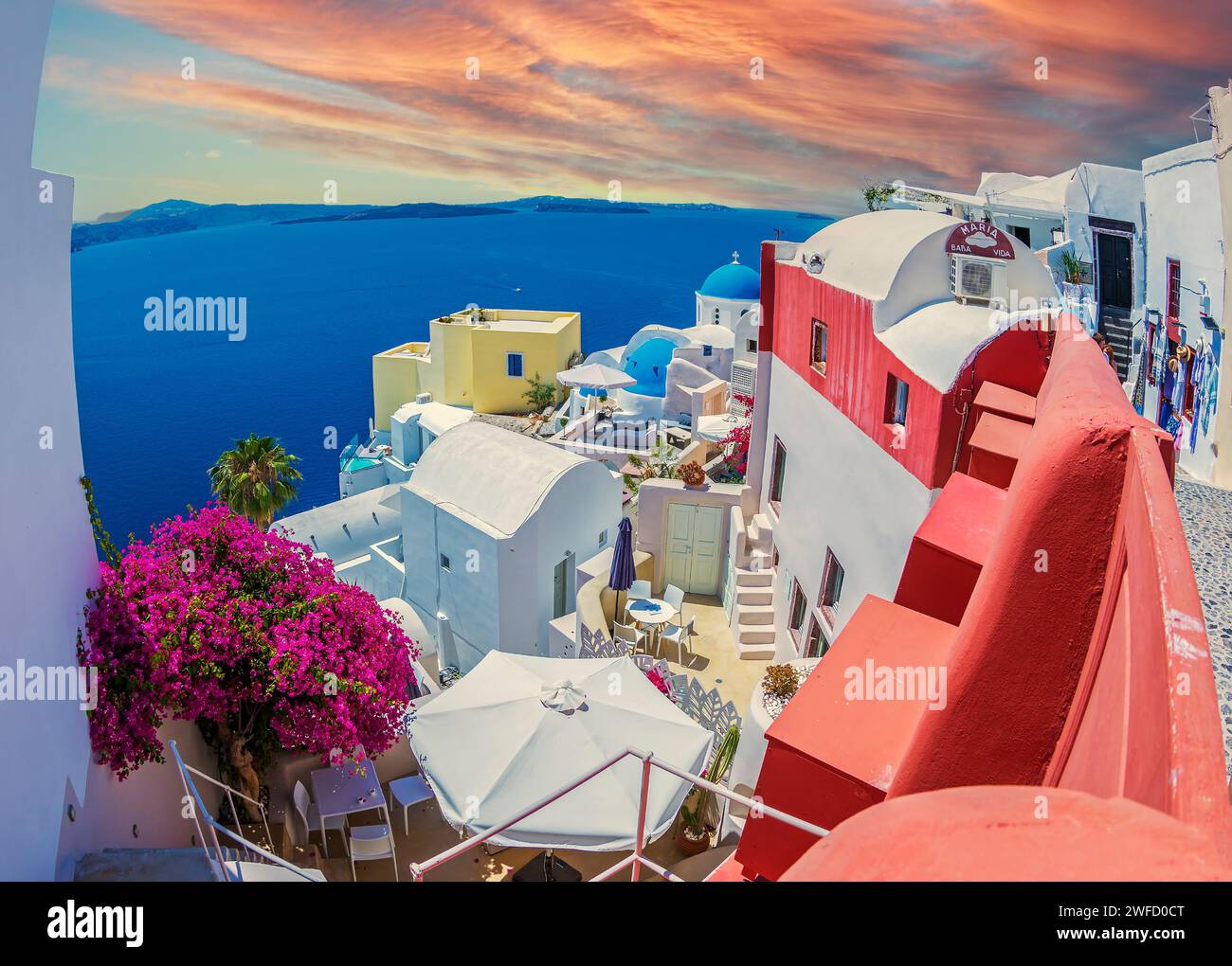 Oia, Santorini island, Greece - June 21, 2021: Typical traditional architecture with houses, domes and churches in afternoon light. Stock Photo