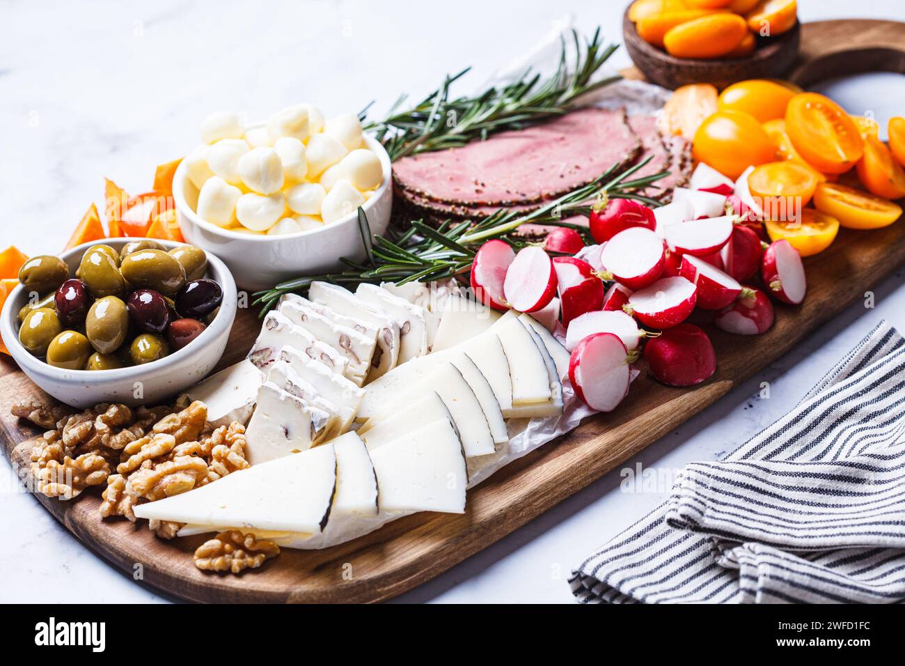 Cheese platter with meat, snacks, vegetables and nuts. Stock Photo