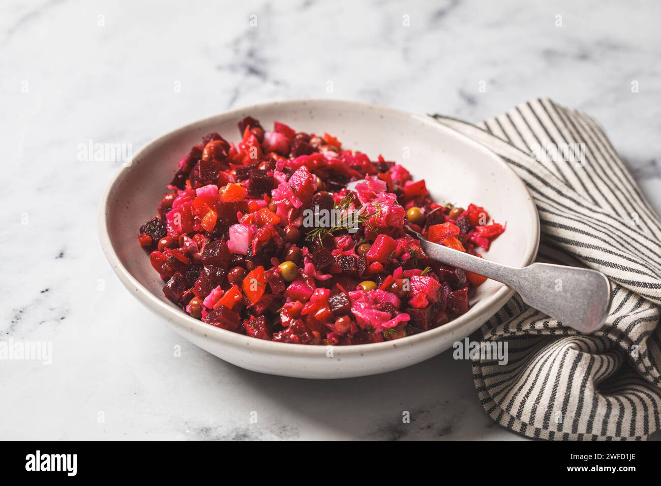 Russian beetroot vinaigrette salad with green peas, boiled vegetables and dill. Stock Photo