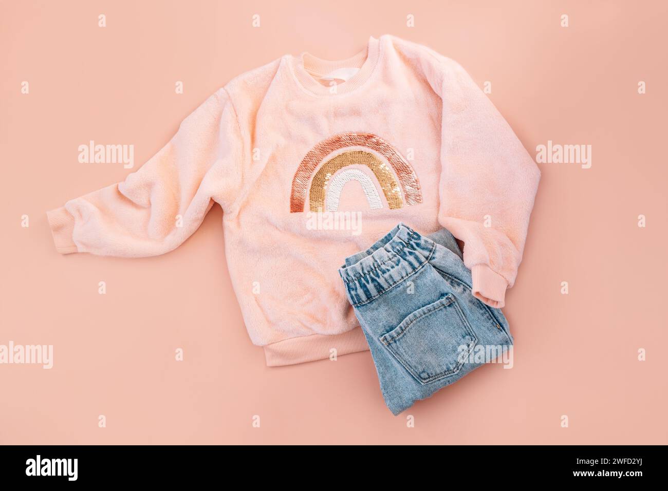Children's pink sweater and blue jeans on a pink background Stock Photo