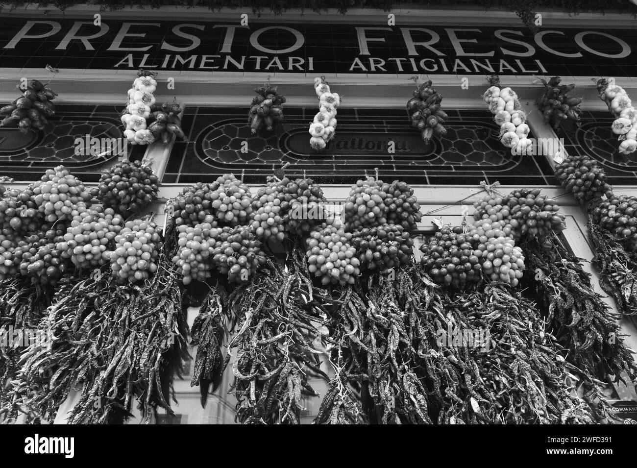 Paris, France - February 21, 2023: Appetizing decor (garlands of cherry tomatoes, dry peppers) at entry to traditional Italian restaurant. Black white Stock Photo