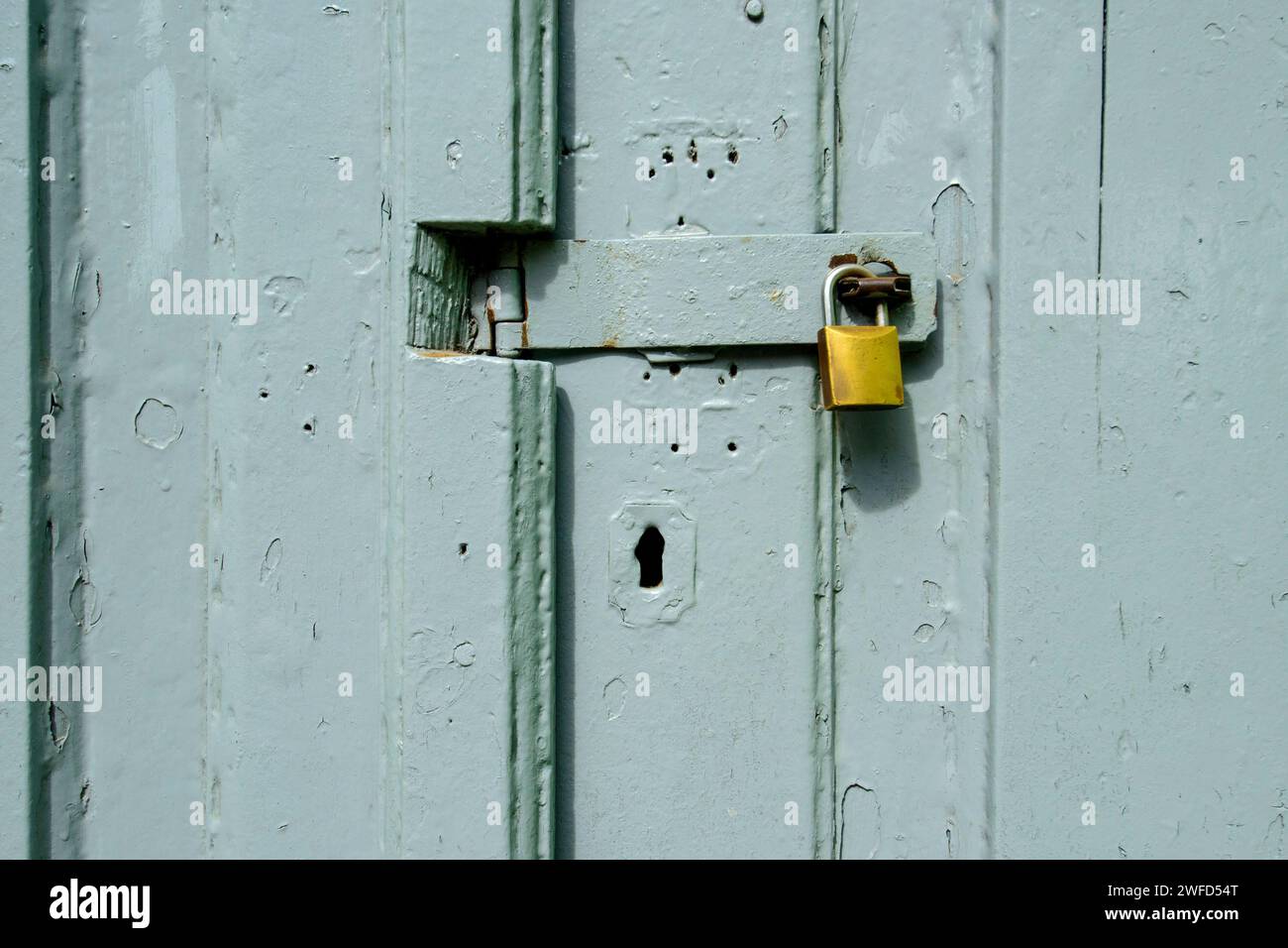 Padlock on gray wooden gate forming a textured background. Stock Photo