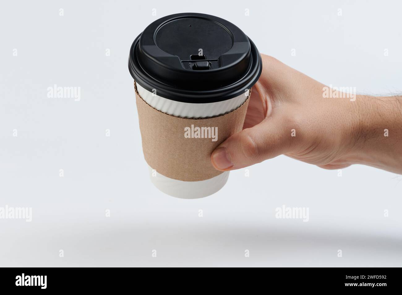 Hand hold paper cup with sleeve side view isolated on white studio ...