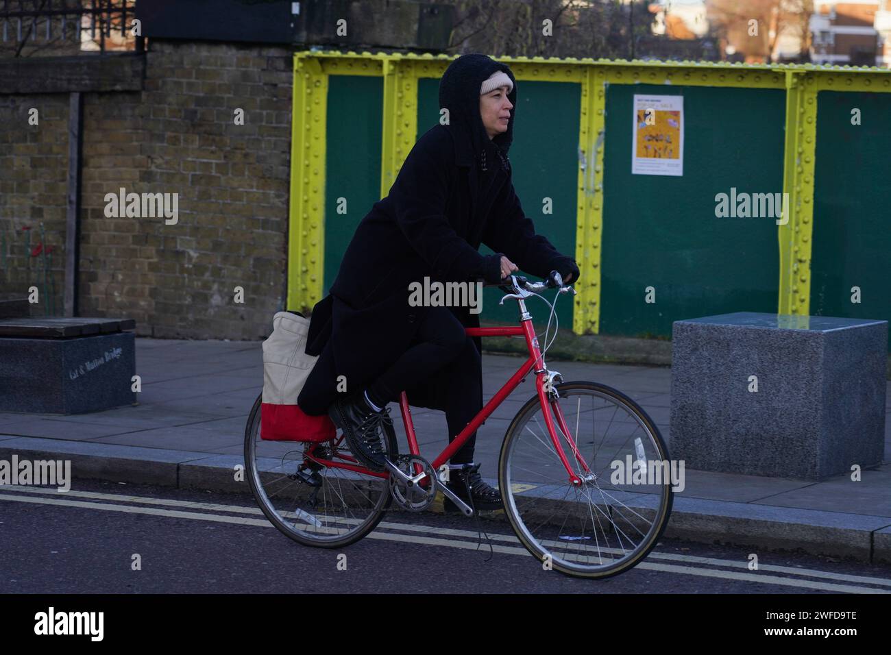A white female bike rider commutes in Hackney, East London in the early morning winter sun. Stock Photo