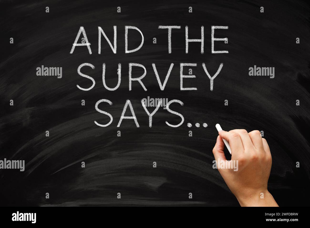 Hand writing And The Survey Says on chalkboard. Customer evaluation feedback results concept. Stock Photo