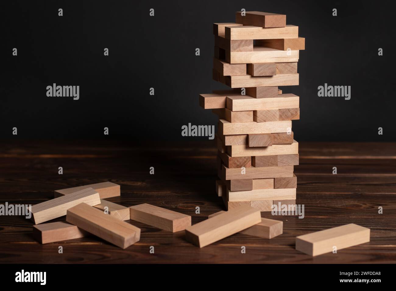 Jenga tower made of wooden blocks on wooden background, space for text. Stock Photo