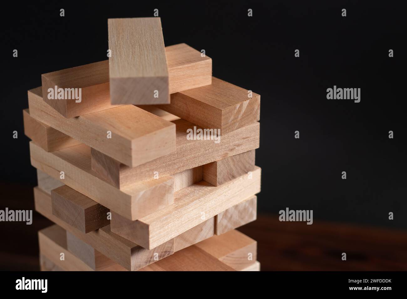 Jenga tower made of wooden blocks on dark background, space for text. Stock Photo