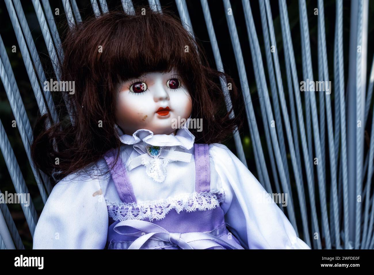 Classic Vintage toy doll with purple dress and ruffle blouse in a dark moody tone Stock Photo