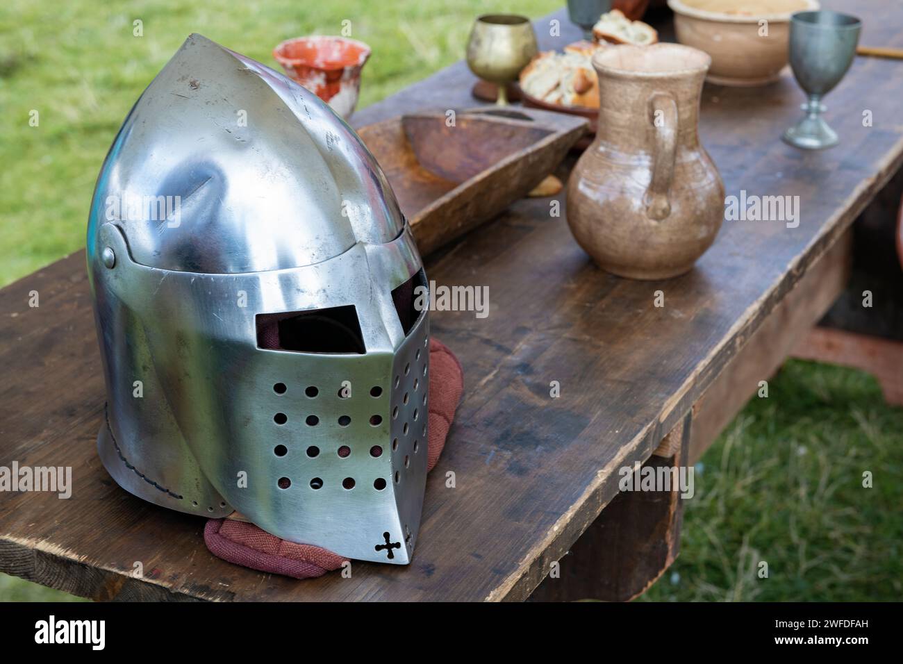 Medieval knight's helmet on the edge of a wooden table Stock Photo