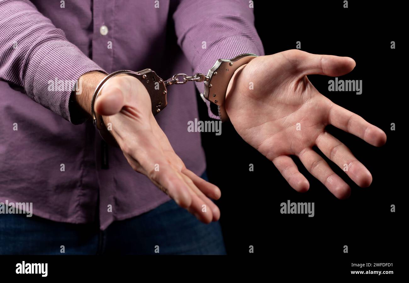 Businessman in handcuffs arrested for financial fraud, sitting in interrogation room. Stock Photo