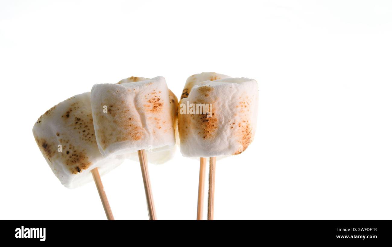 Bamboo sticks with roasted marshmallows on white backgrop Stock Photo