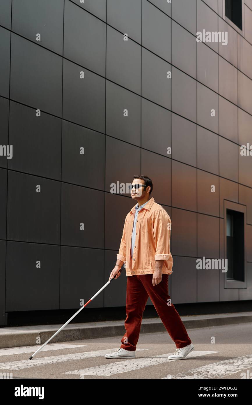 attractive indian blind man in orange jacket with glasses and stick