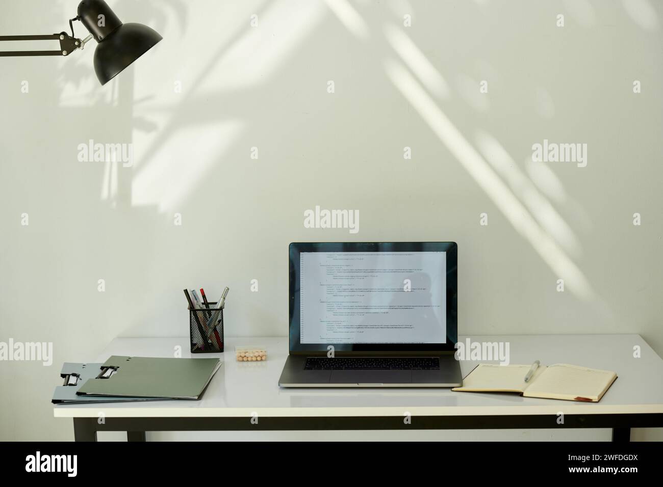 Opened laptop with programming code on screen on desk of freelancer Stock Photo