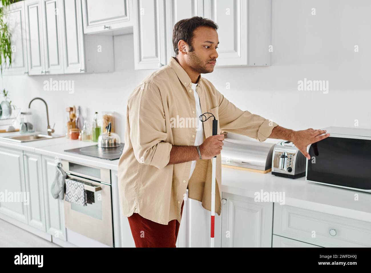 attractive indian man with visual impairment wearing cozy homewear and preparing food, disabled Stock Photo