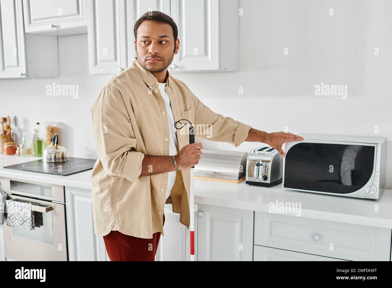 good looking indian man with visual impairment wearing cozy homewear and preparing food, disabled Stock Photo