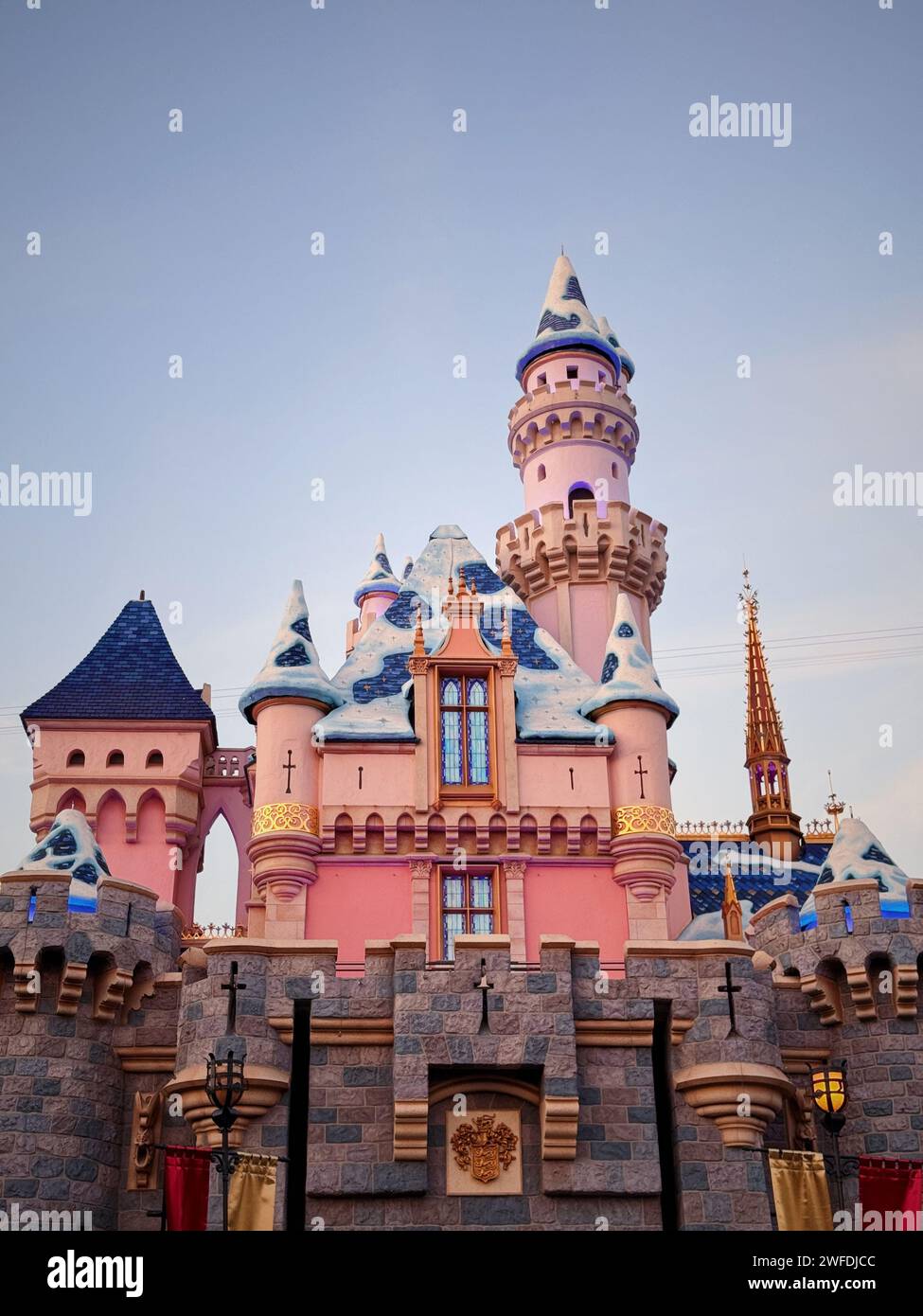 Front view of a charming castle adorned with pink and blue hues, accentuated by a pristine layer of snow Stock Photo
