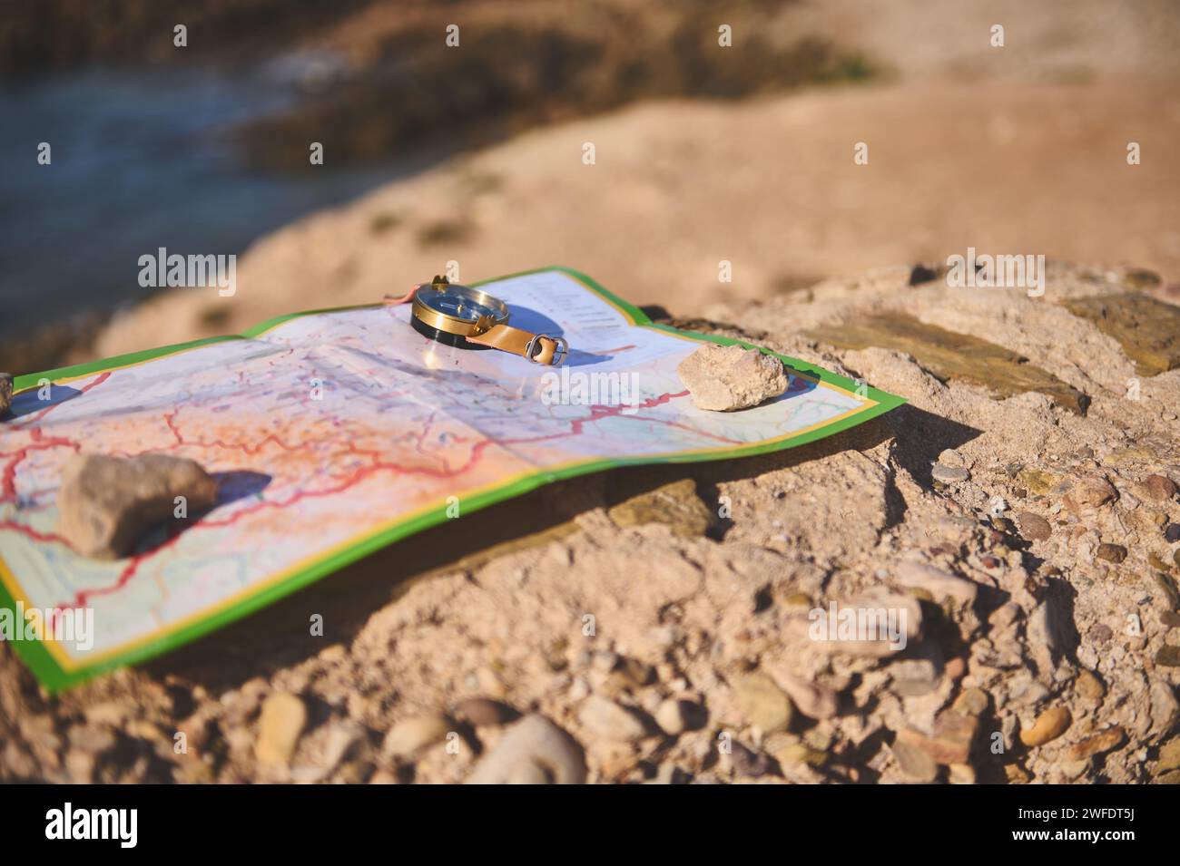 A geographic map and nautical equipment, a compass on the rock against the background of a cliff overlooking the Atlantic rock beach. Trip. Tour touri Stock Photo