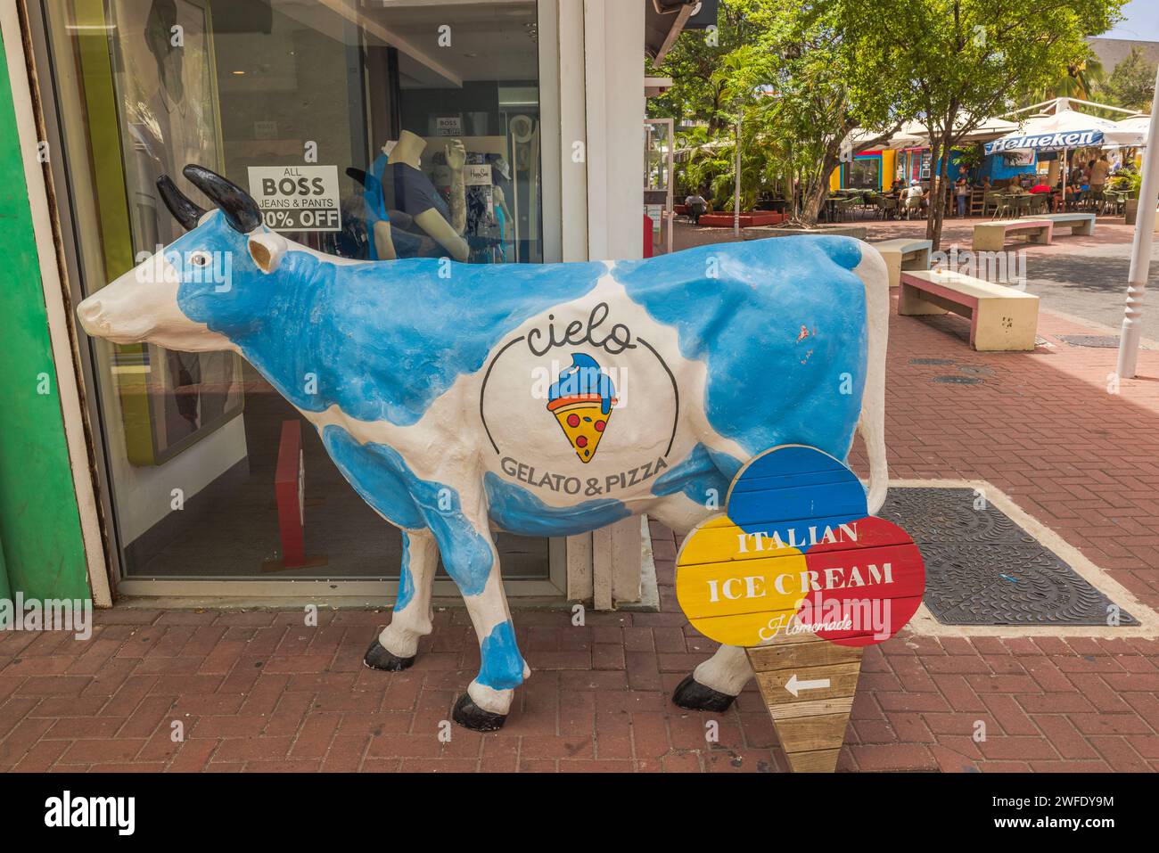 A statue of a white-and-blue cow near an ice cream shop window in downtown Willemstad, Curacao. Stock Photo