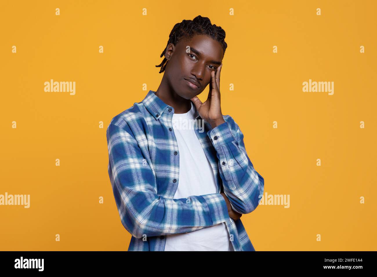 Pensive young black man touching face and looking at camer Stock Photo