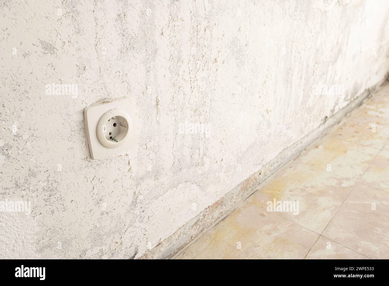 Detail of an electric outlet on a damaged wall and floor ready to be restored. Home renovation concept Stock Photo