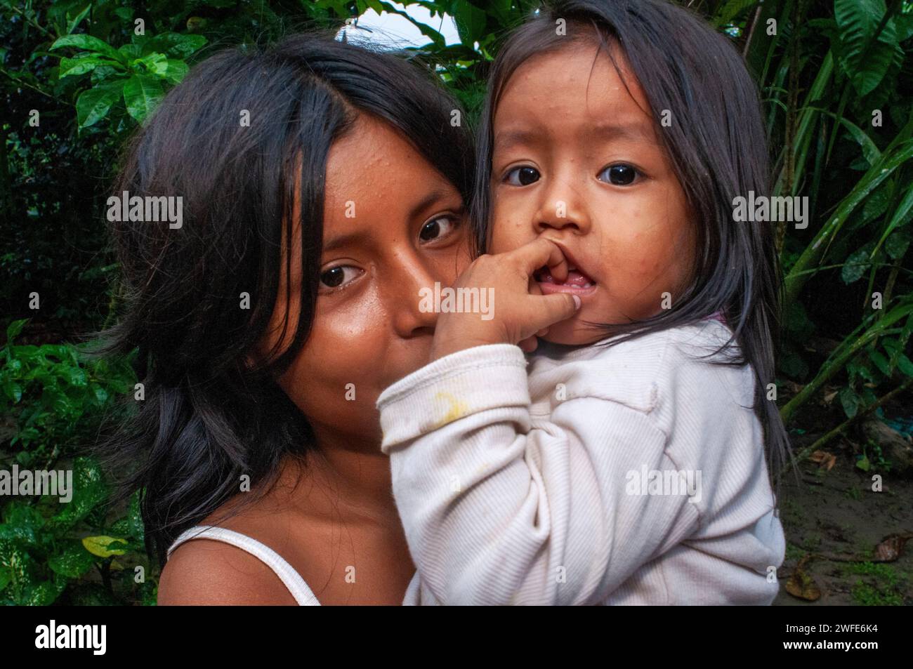 A girl takes care of her sister while her parents work, local family in the riverside village of Timicuro I. Iqutios peruvian amazon, Loreto, Peru Stock Photo