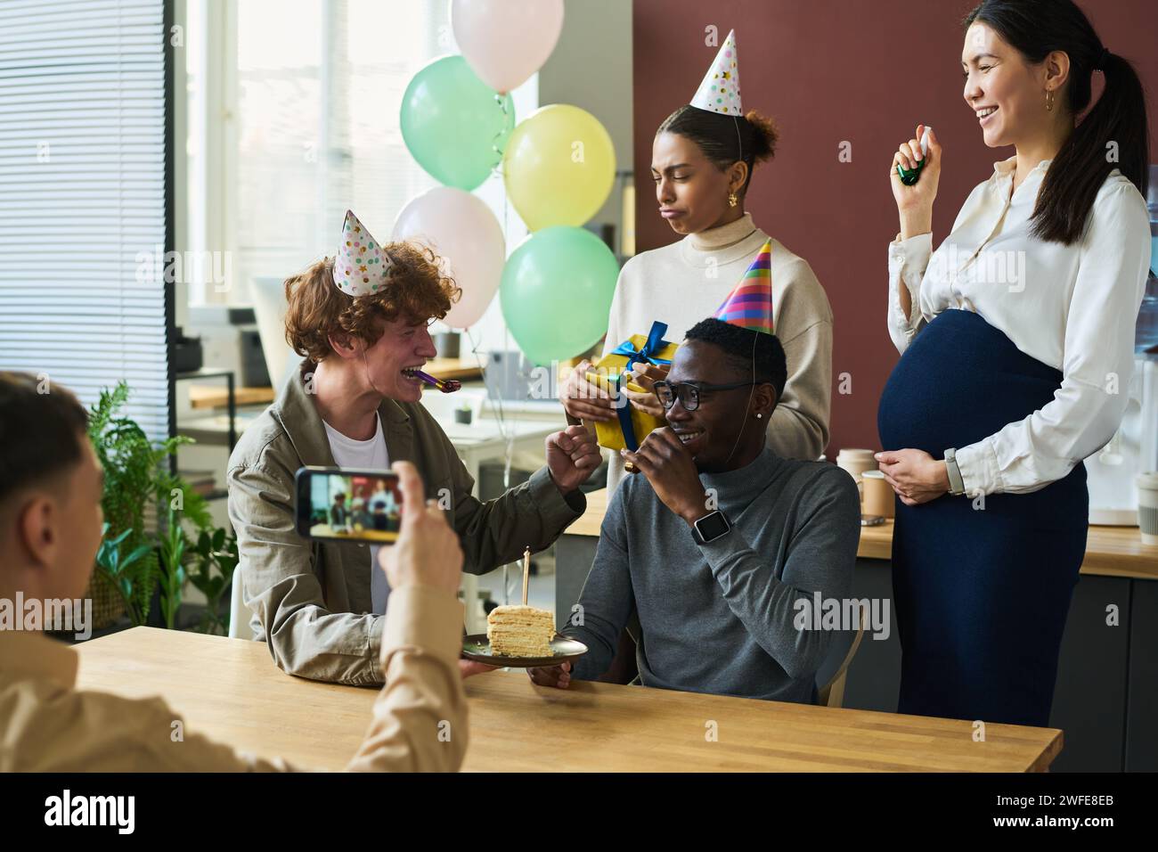 Group of happy young intercultural colleagues in birthday caps ...